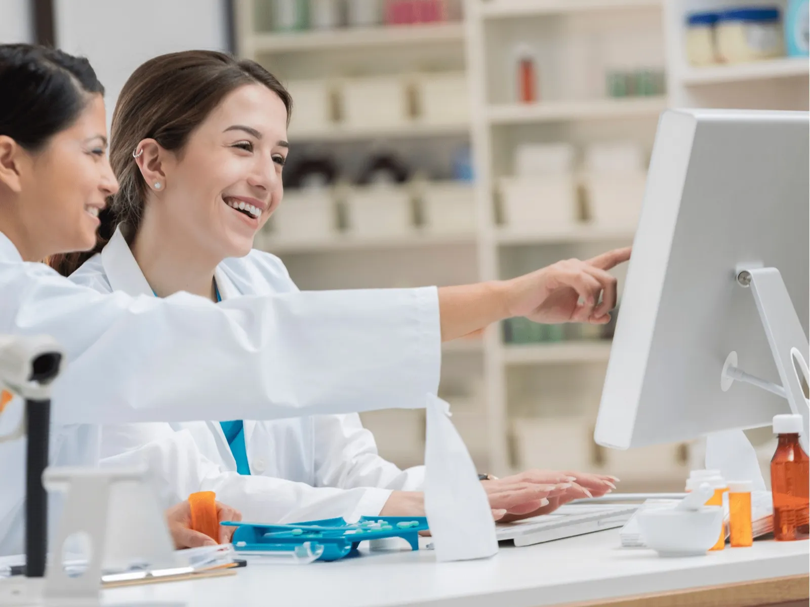 Pharmacists reviewing claims data together on a pharmacy monitor
